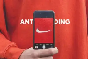 Persona sosteniendo un móvil que muestra la palabra anti‑branding, simbolizando autenticidad y rechazo a los slogans